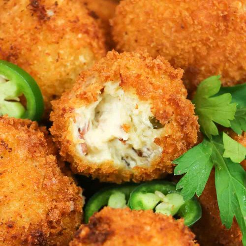 Golden-brown fried jalapeño popper bites with creamy cheese filling, one cut open to show interior, garnished with parsley