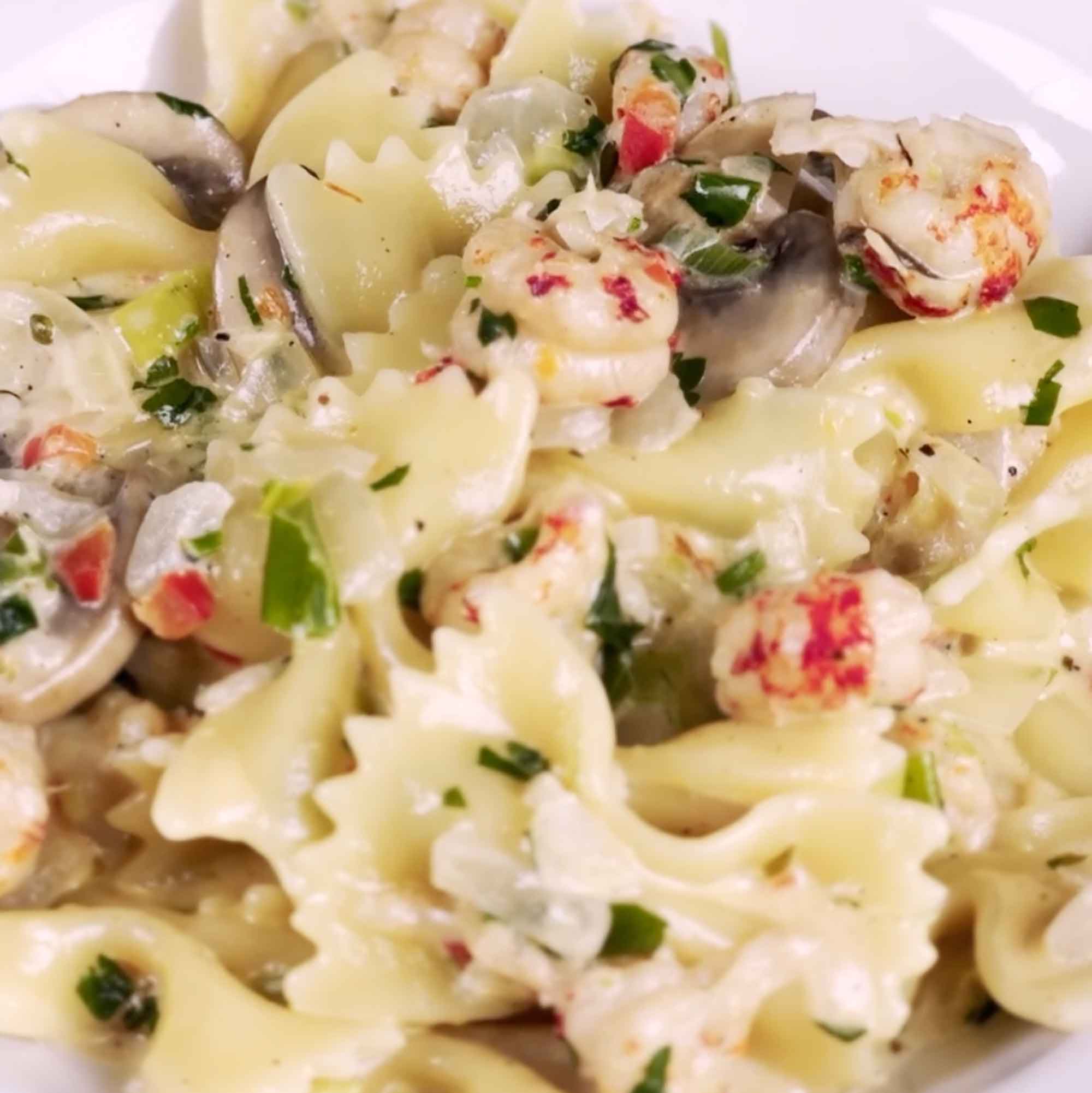 Creamy pasta dish with crawfish, herbs, and red pepper flakes in a white bowl