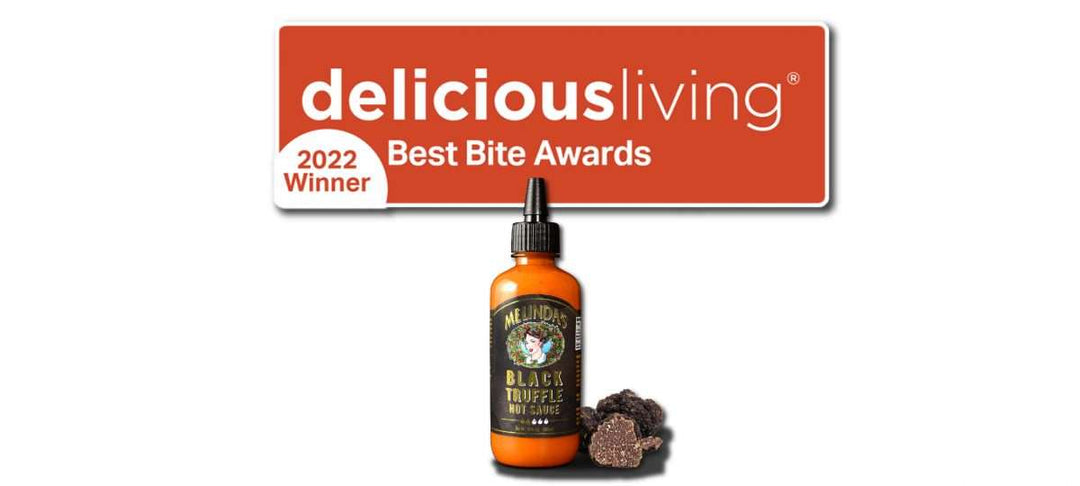 Bottle of Melinda's Black Truffle Hot Sauce with truffle pieces and 2022 Delicious Living Best Bite Awards Winner badge