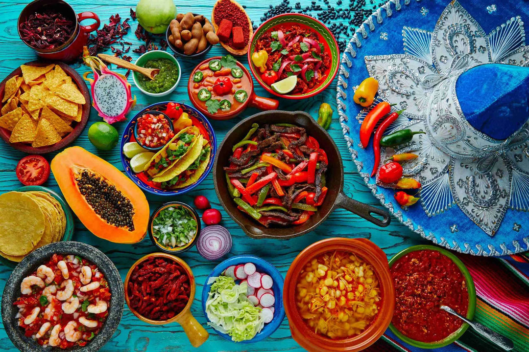 Colorful spread of spicy Mexican dishes including fajitas, salsas, tortillas, and chili peppers on bright blue table