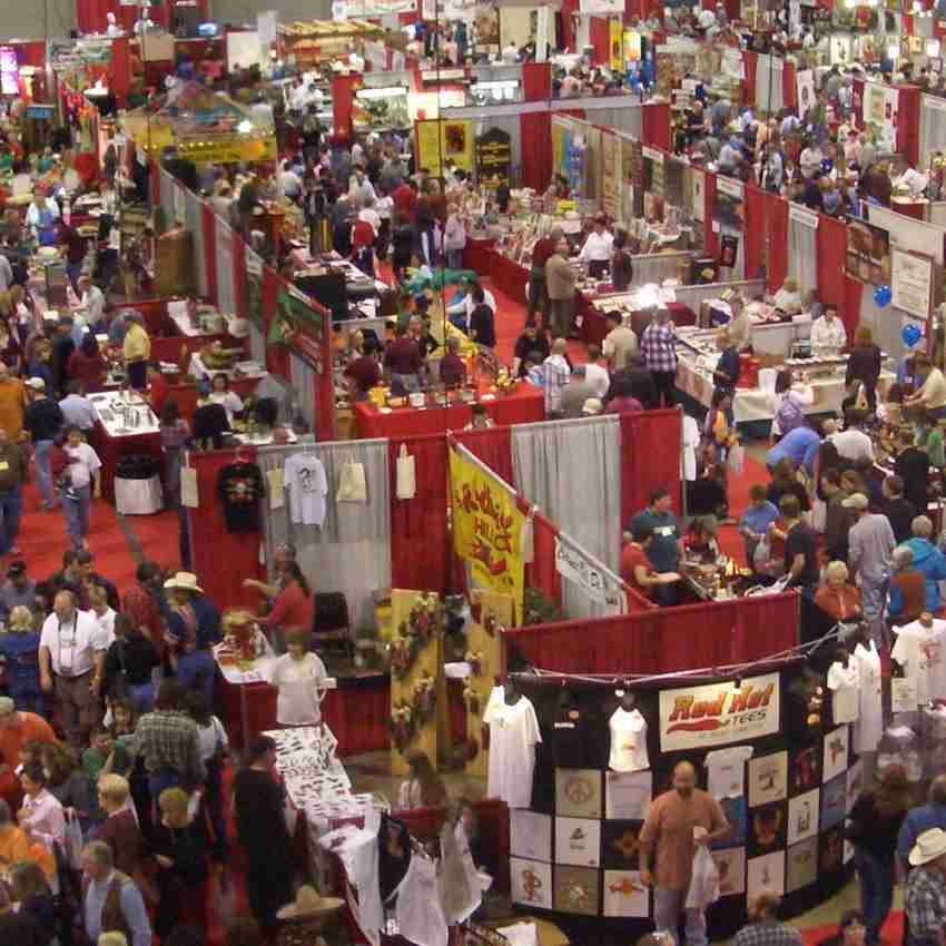 Crowded trade show floor with red booth dividers and hundreds of attendees browsing food vendor displays and samples
